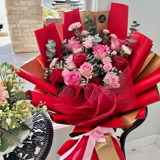 Red and pink rose bouquet with blush ribbon